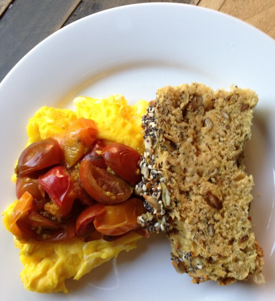 Simple weekend breakfast of scrambled eggs topped with quick-sautéed cherry tomatoes with a slice of homemade whole-grain seeded soda bread